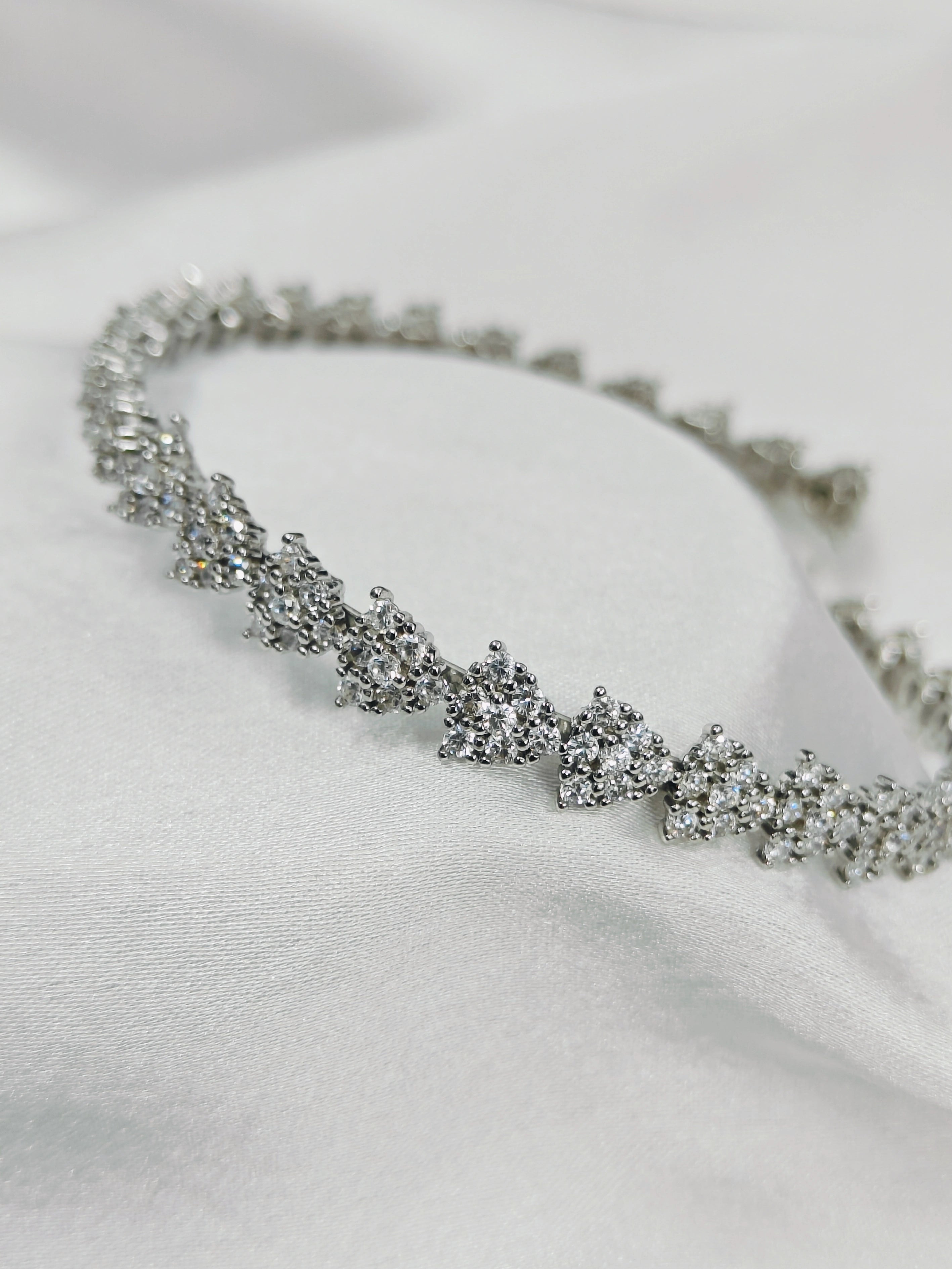 Silver bracelet with clear stones on a white fabric background